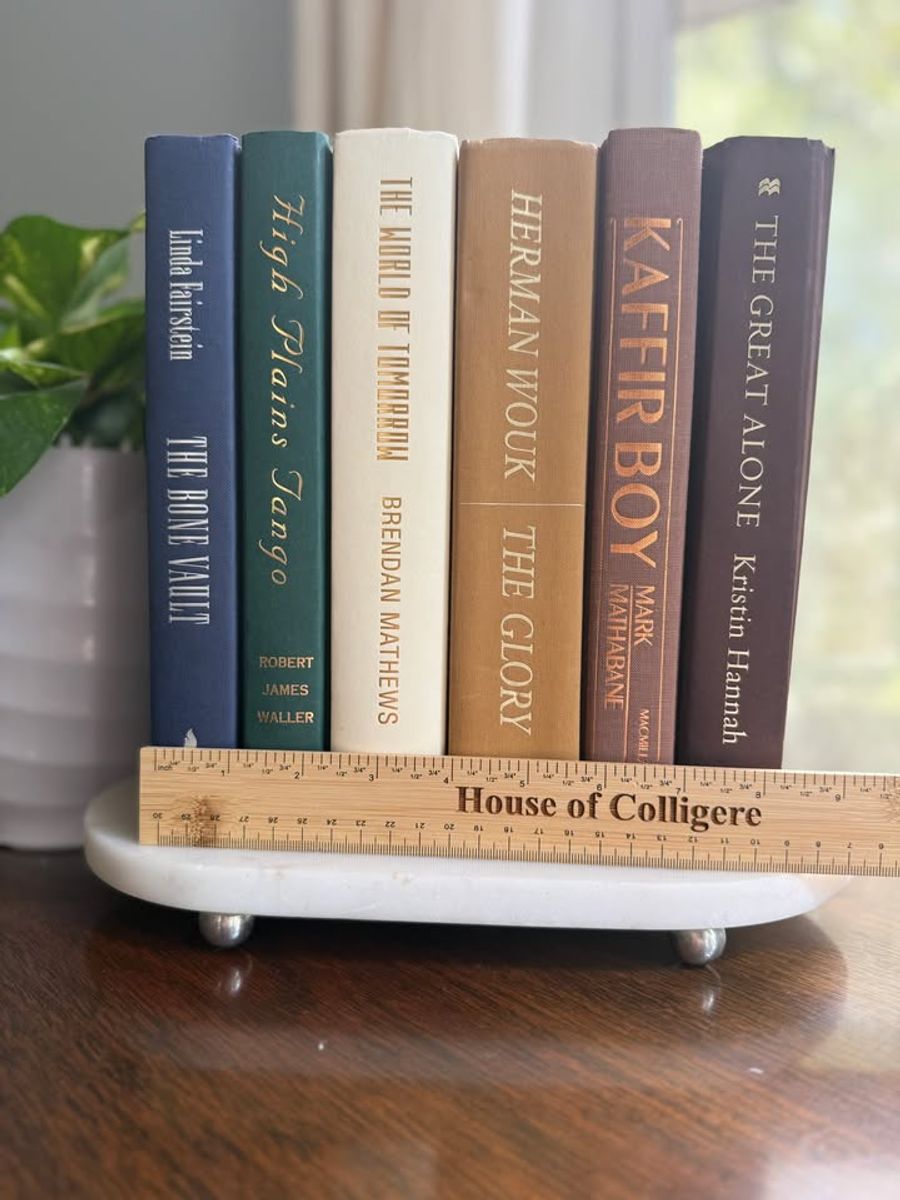 Curated collection of rich brown, hunter green, deep navy, and warm ivory books with classic gold accents.