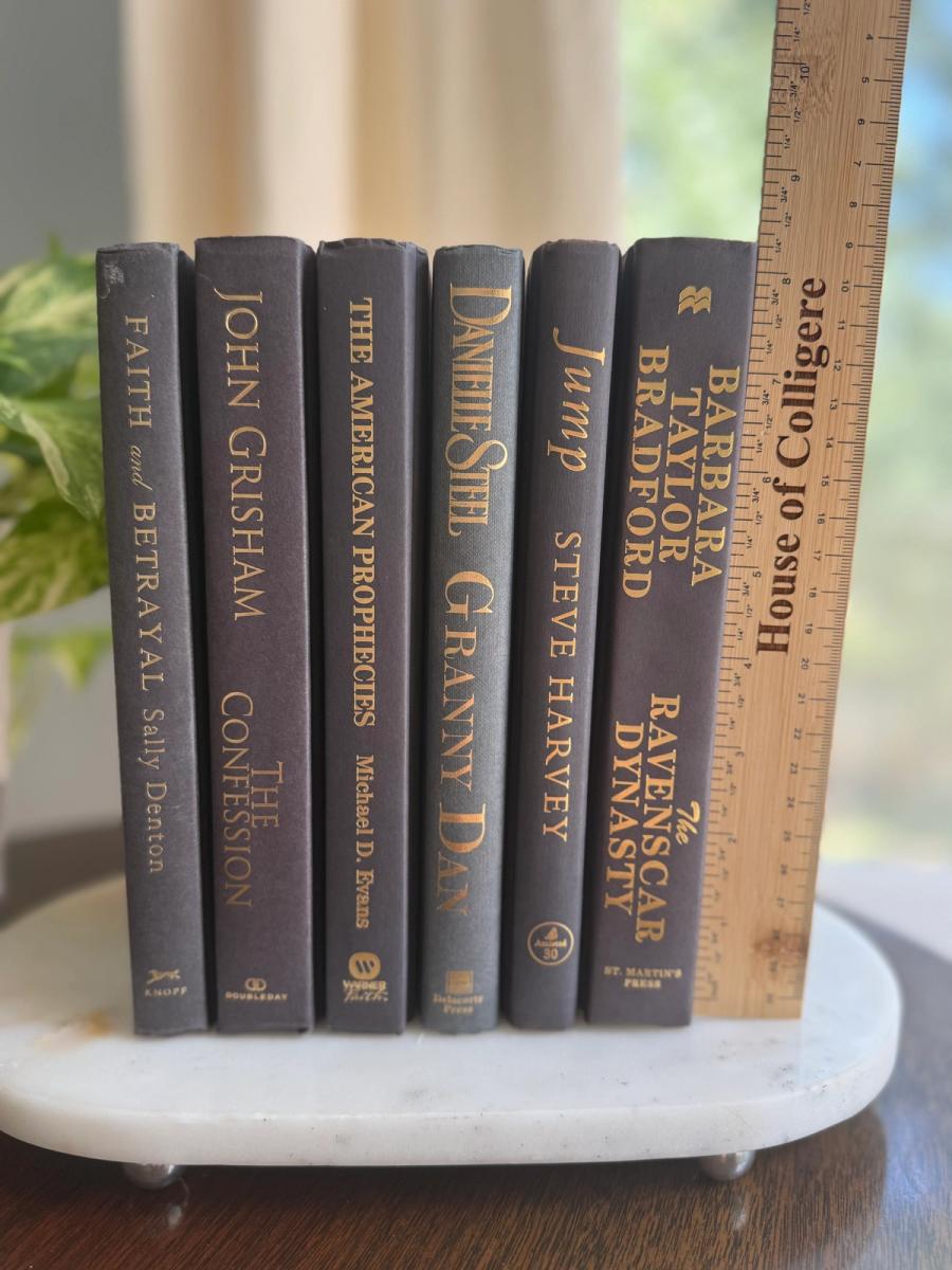 Curated collection of rich charcoal and black books with warm gold lettering and dramatic tonal depth.