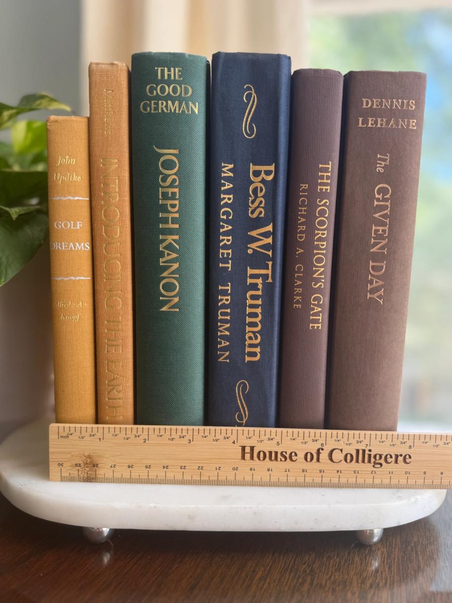 Curated collection of rich brown, hunter green, deep navy, and warm ivory books with classic gold accents.