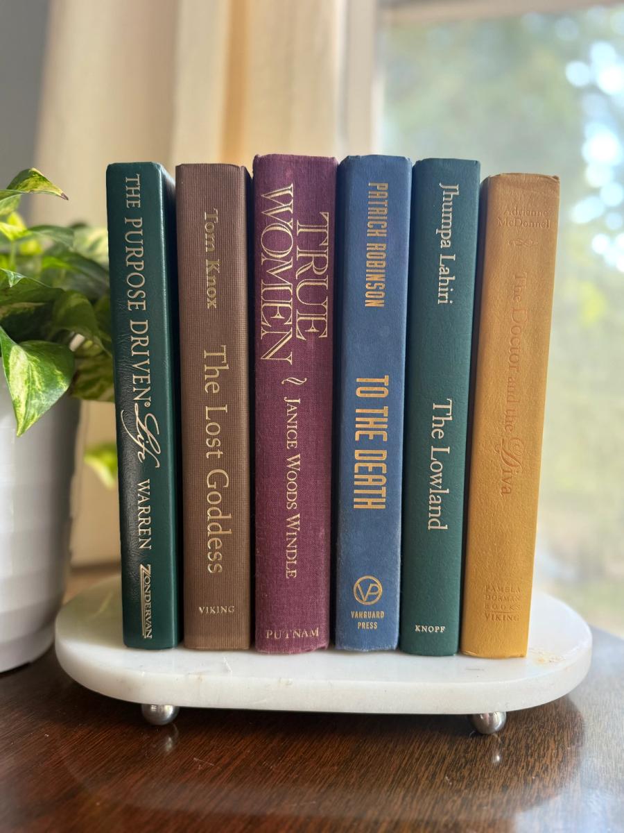 Curated collection of rich brown, hunter green, deep navy, and warm ivory books with classic gold accents.
