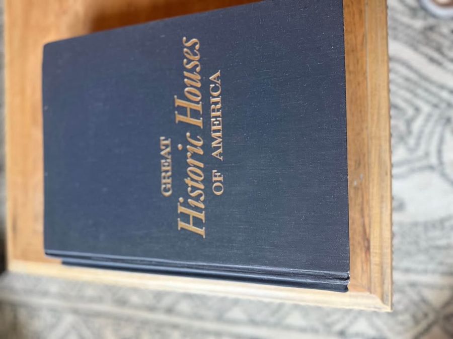 Curated pair of oversized black hardcover books with deep charcoal-black covers, warm aged page edges, and understated gold and cream lettering.