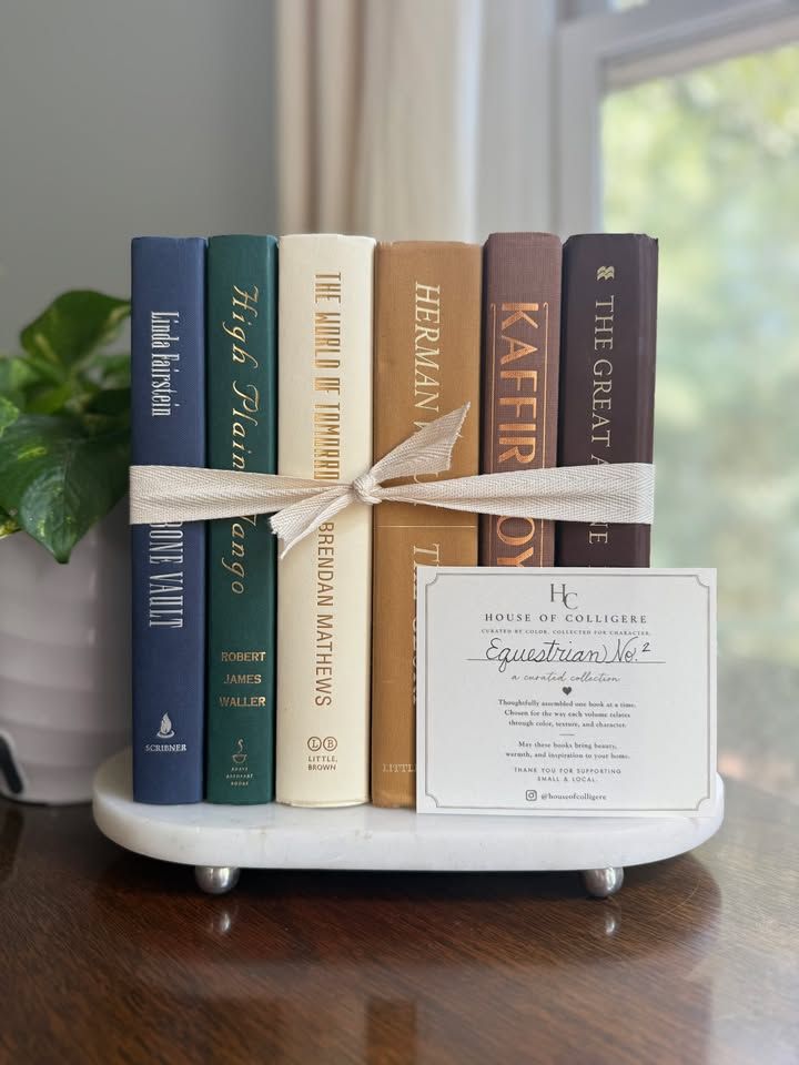 Curated collection of rich brown, hunter green, deep navy, and warm ivory books with classic gold accents.