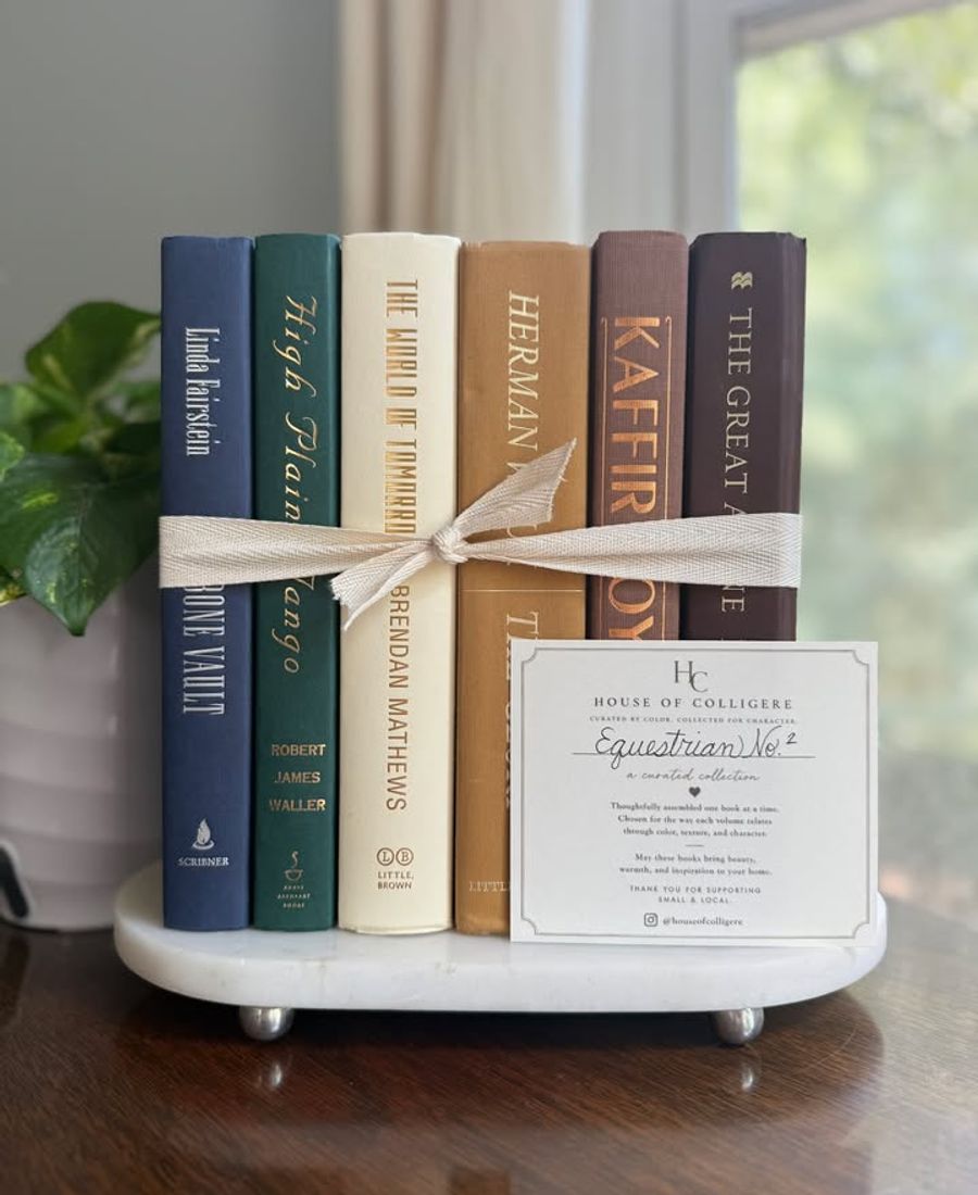 Curated collection of rich brown, hunter green, deep navy, and warm ivory books with classic gold accents.