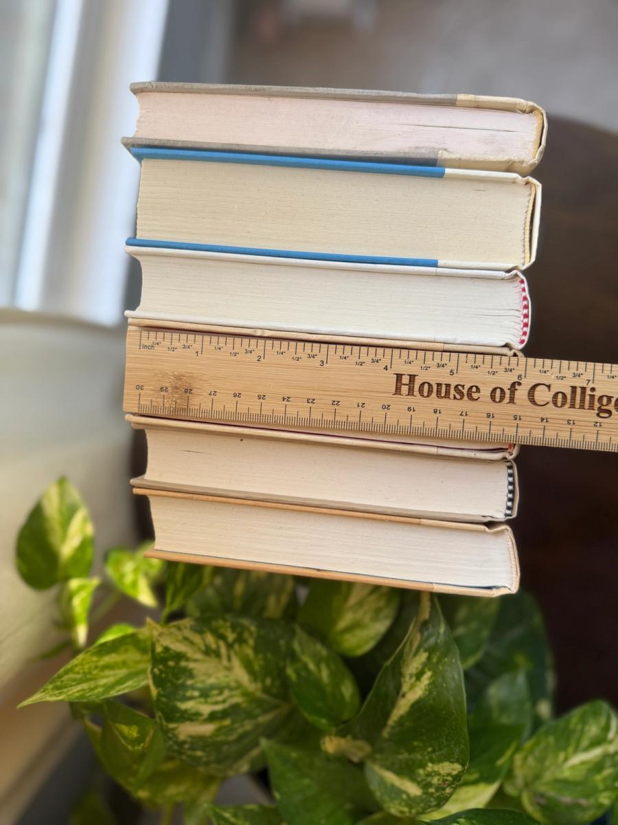 Curated collection of white, ivory, and cream hardcover books with soft neutral tones on a coffee table beside a plant