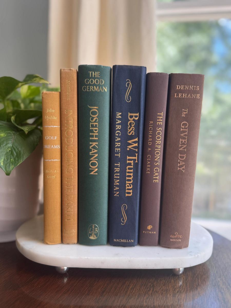 Curated collection of rich brown, hunter green, deep navy, and warm ivory books with classic gold accents.