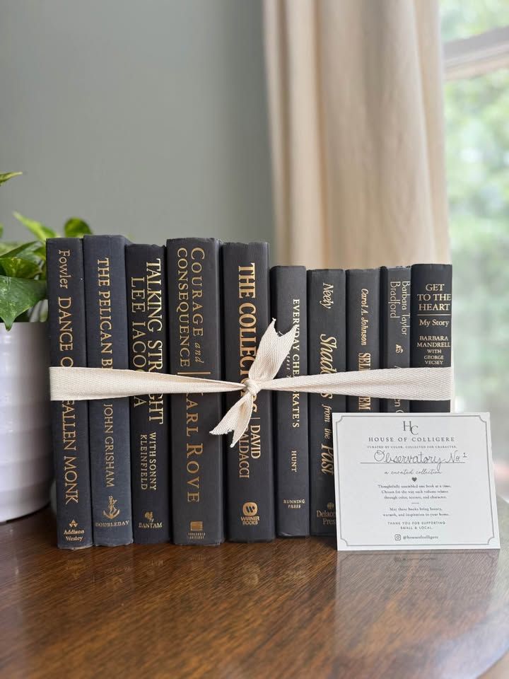 A collection of 10 hardcover books in rich charcoal and black cloth bindings with warm gold lettering. 