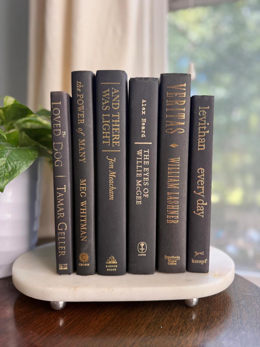Curated collection of rich charcoal and black books with warm gold lettering and dramatic tonal depth.