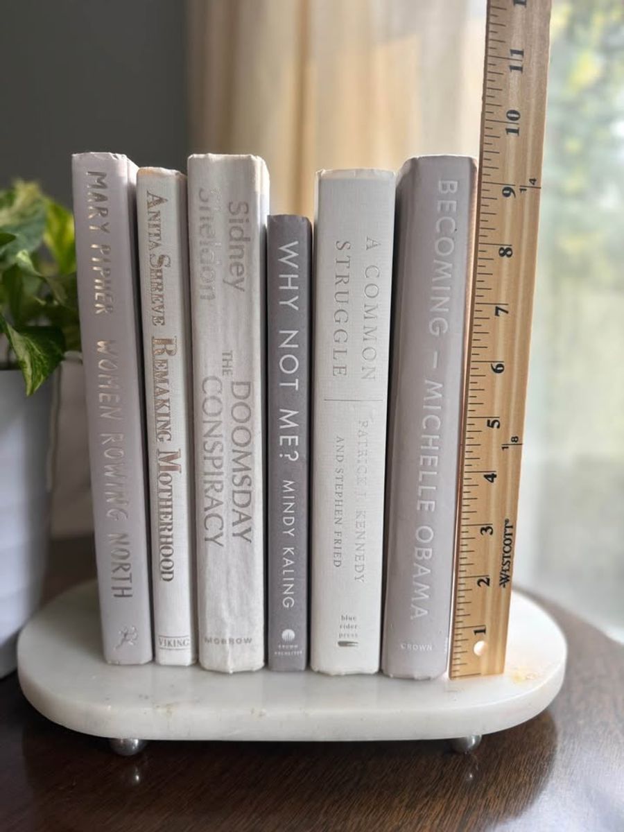 Curated collection of soft white, pale gray, warm greige, and stone-toned books with subtle tonal variation.