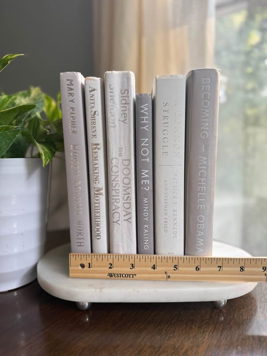 Curated collection of soft white, pale gray, warm greige, and stone-toned books with subtle tonal variation.