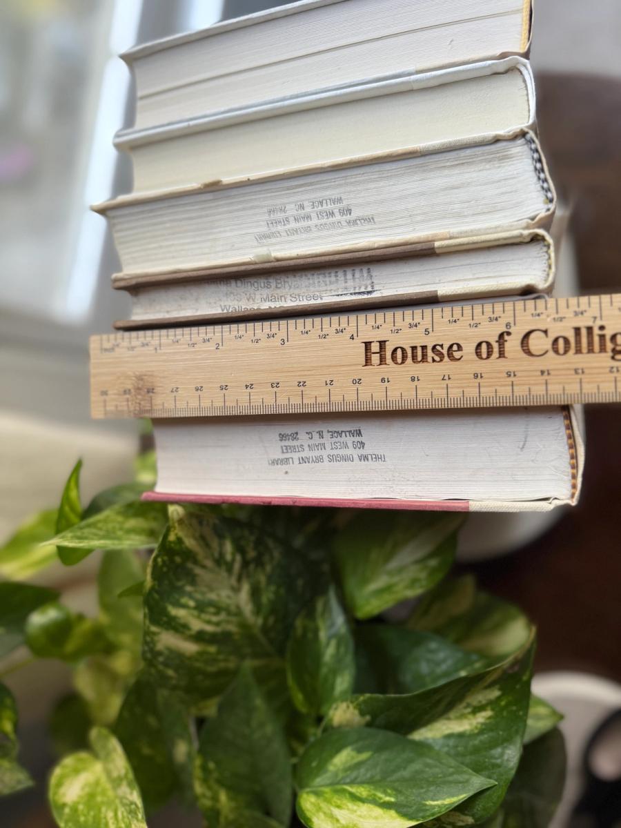 Curated collection of white, ivory, and cream hardcover books with soft neutral tones on a coffee table beside a plant 