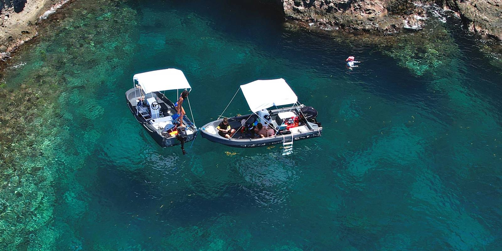Deux bateaux Ride & Sea au mouillage devant une grotte marine, eau turquoise