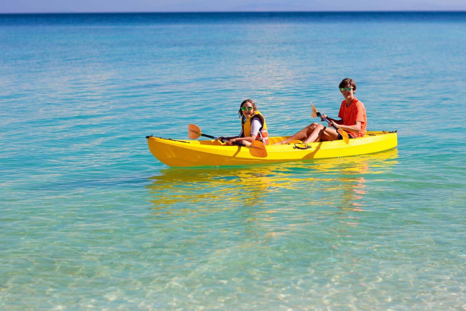 Deux personnes dans un kayak double jaune sur une eau transparente
