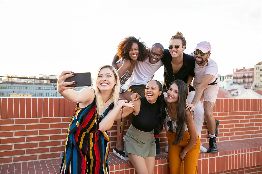 group of young people gathered on a rooftop posing together for a smiling selfie.