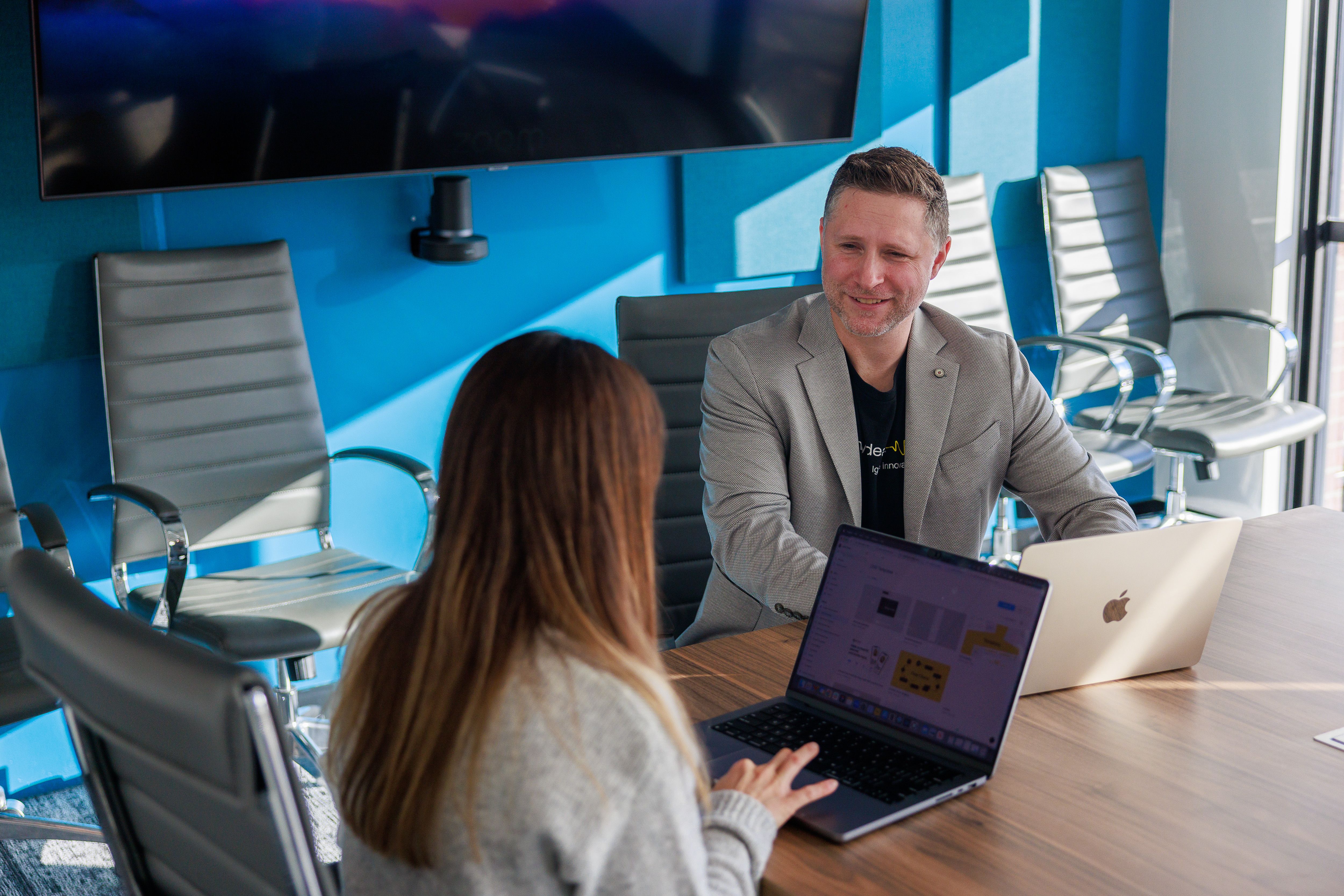 Twenty Ideas CEO Mike Biglan sitting at conference table talking to another team member.