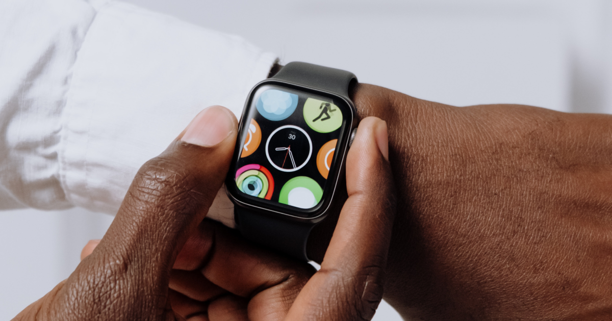 Close up of man's wrist with smartwatch showing analogue clock.