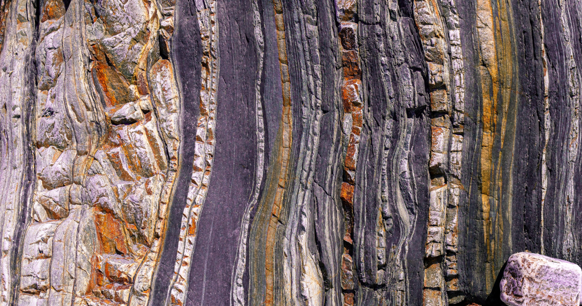 Brightly colored striated rock shown in cross section.