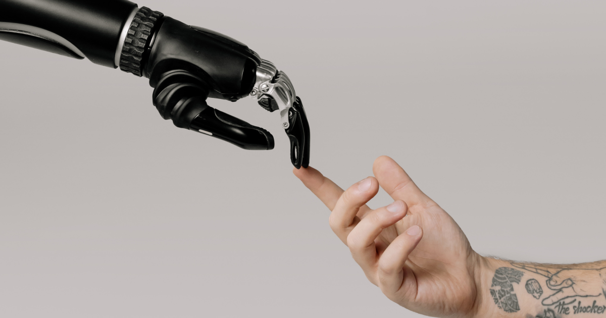 Robot hand reaching out and touching fingers with human hand.