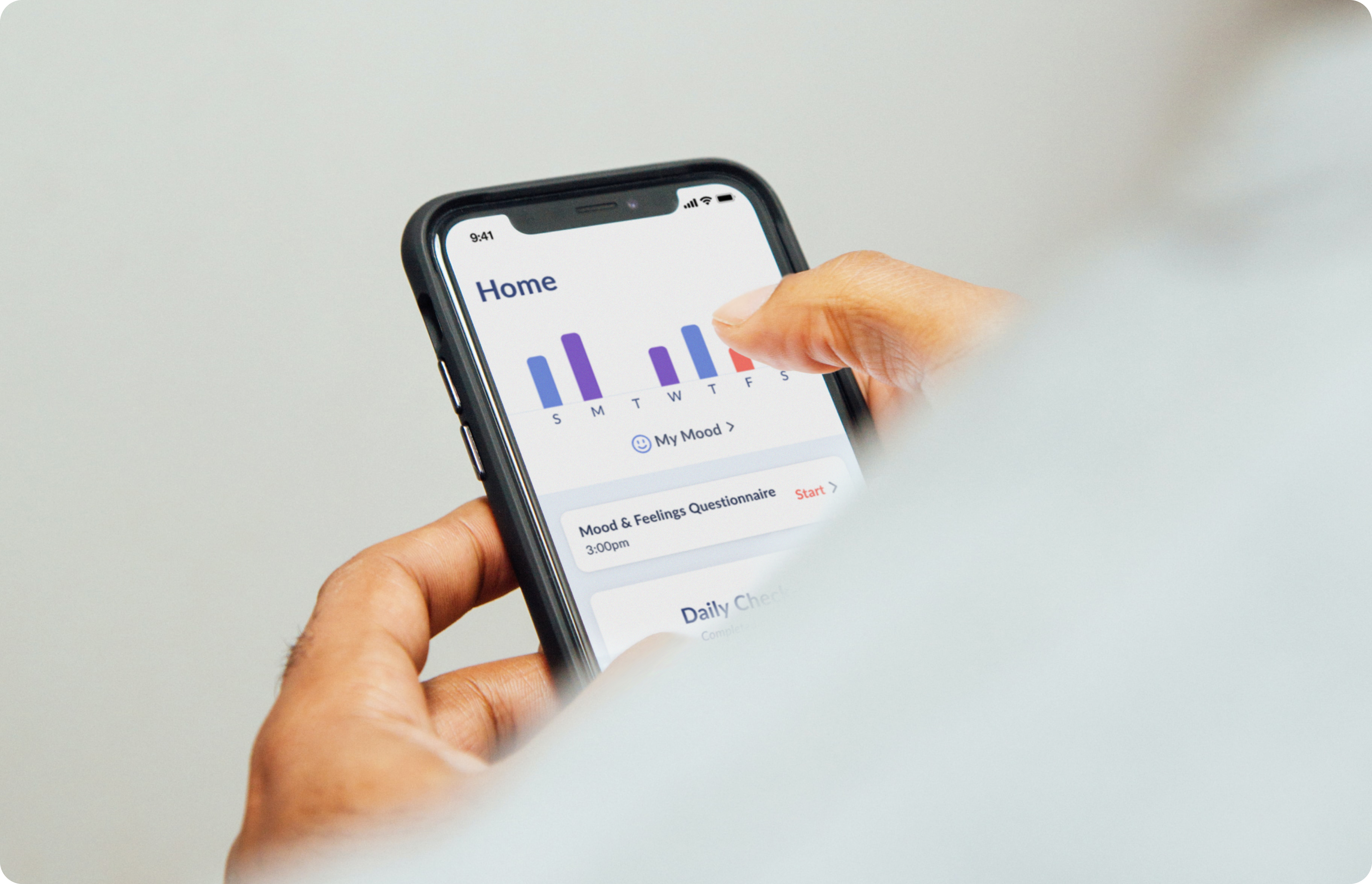 Hands using smartphone displaying Home screen and charts from Ksana mental health monitoring app.