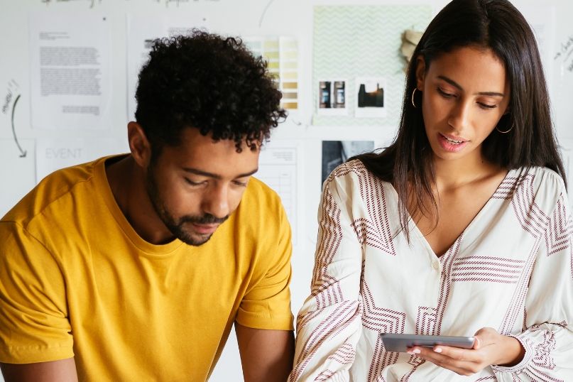 a man and a woman are looking at a cell phone .
