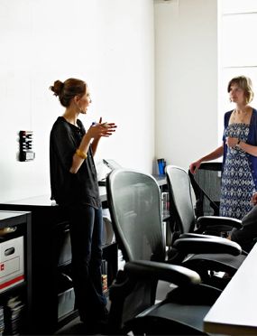 Three people discussing in a bright office with a whiteboard.
