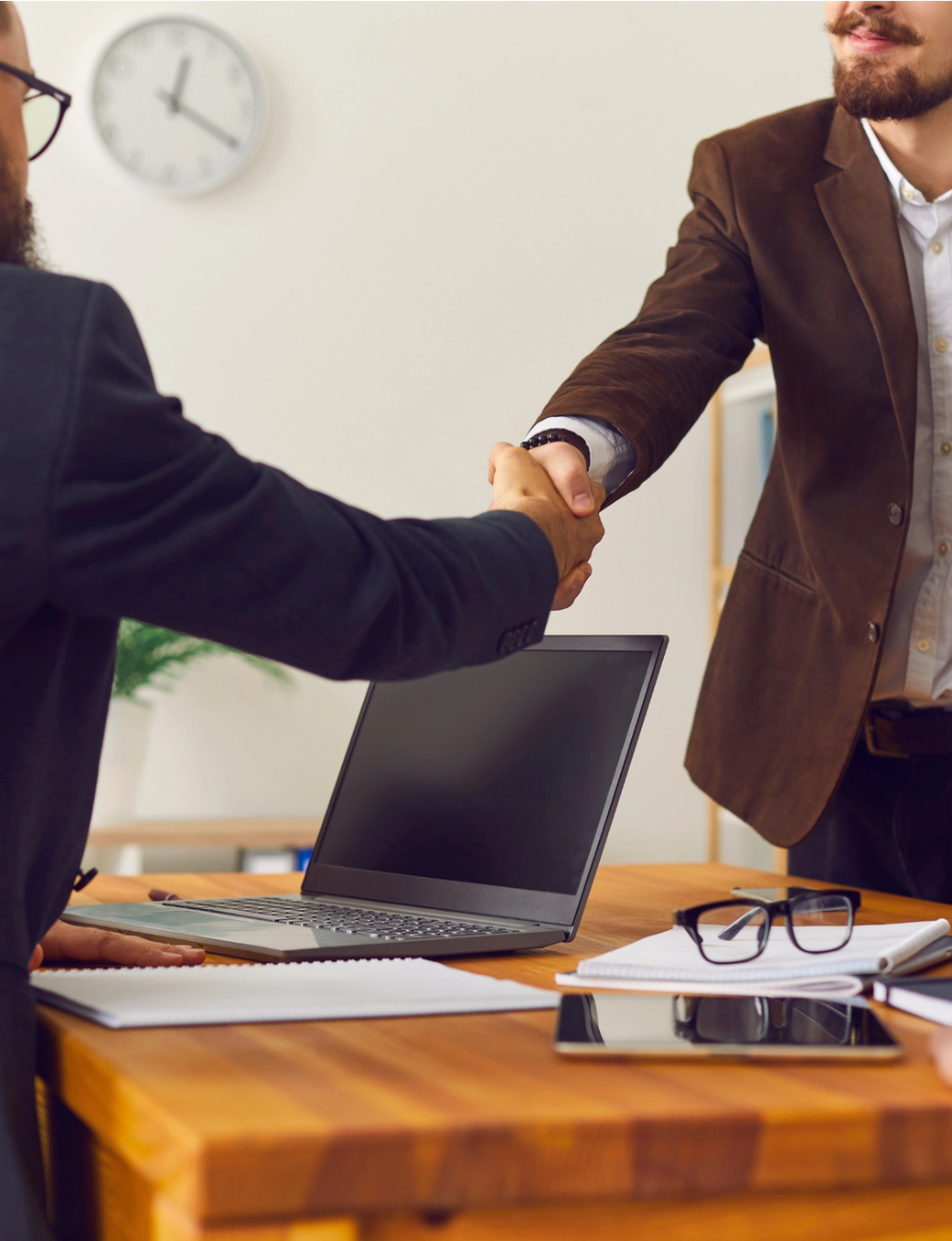 Two businessmen shaking hands across a meeting table.