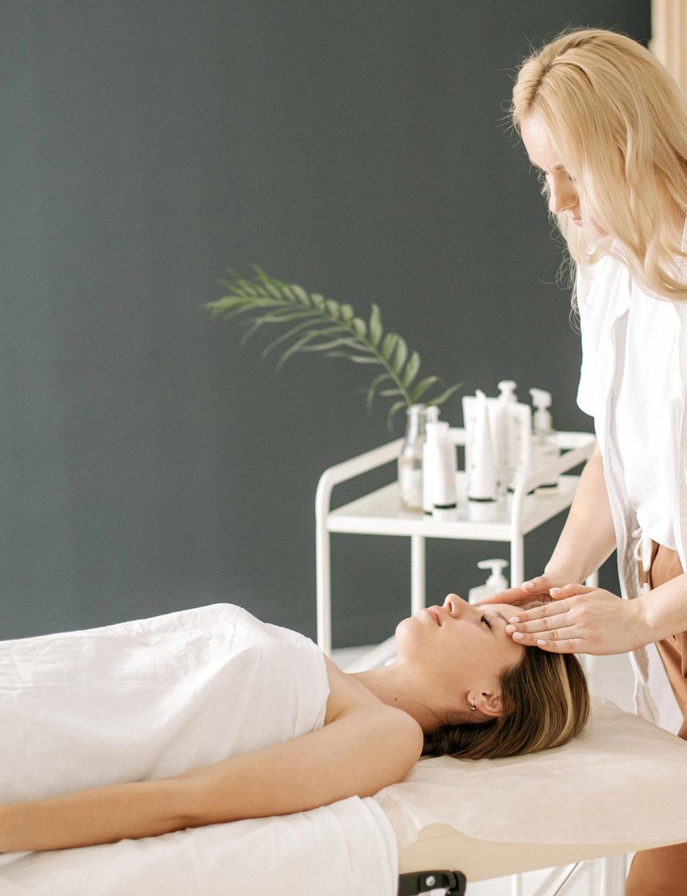 An esthetician performs a facial massage on a client.