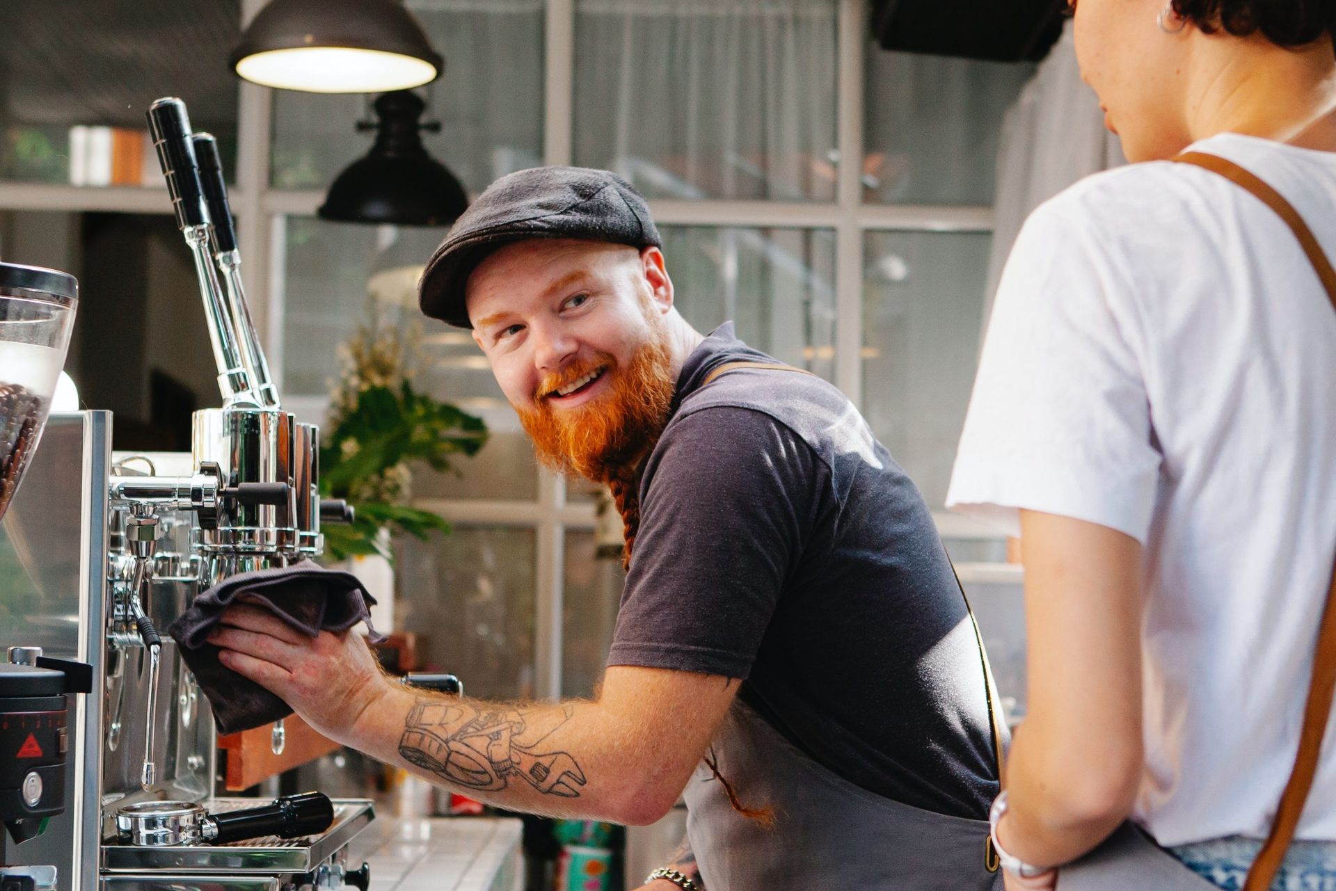 a man with a beard is cleaning a coffee machine in a cafe .