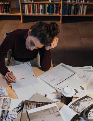 a woman is sitting at a desk with a laptop and papers .