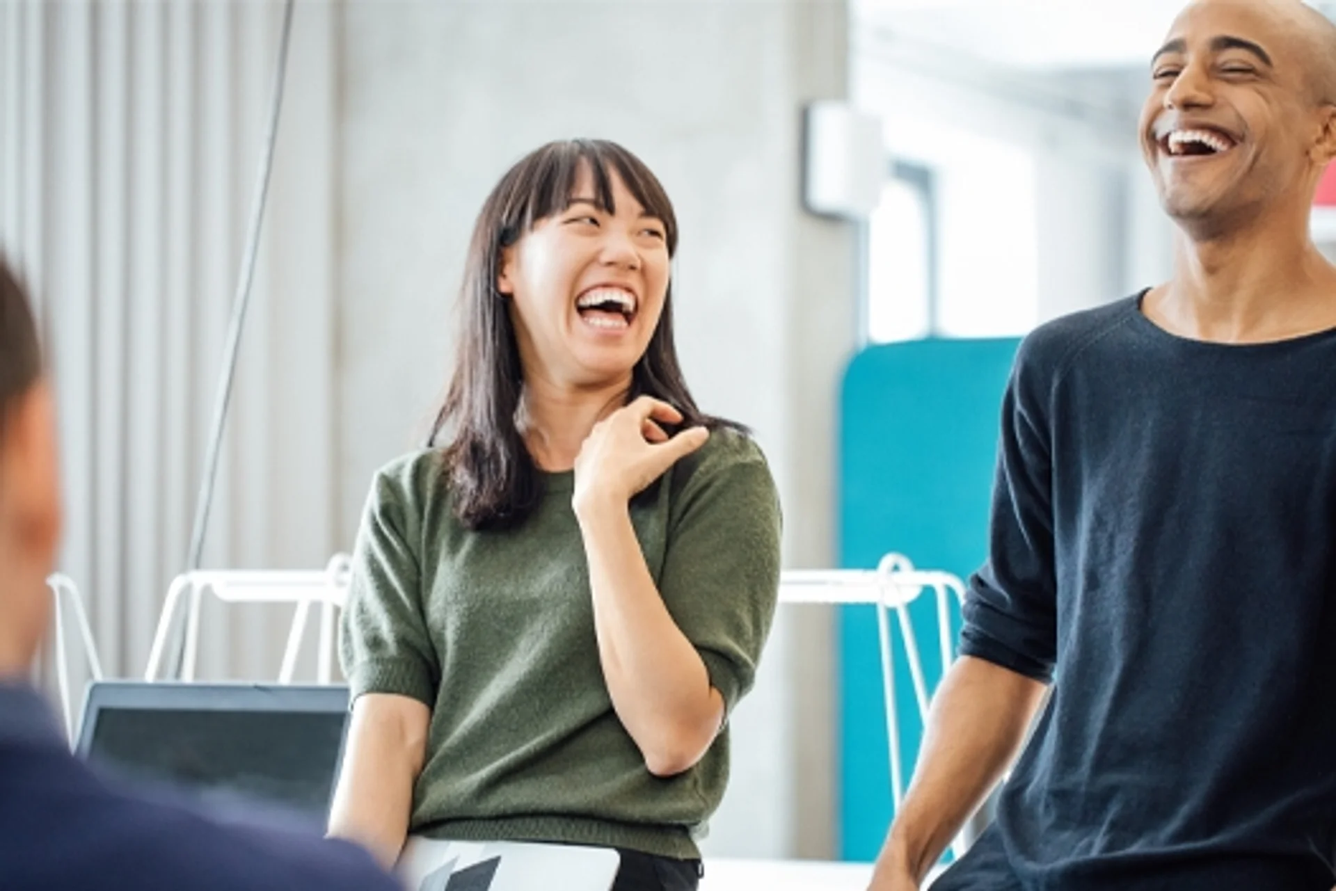 a man and a woman are laughing together in an office .
