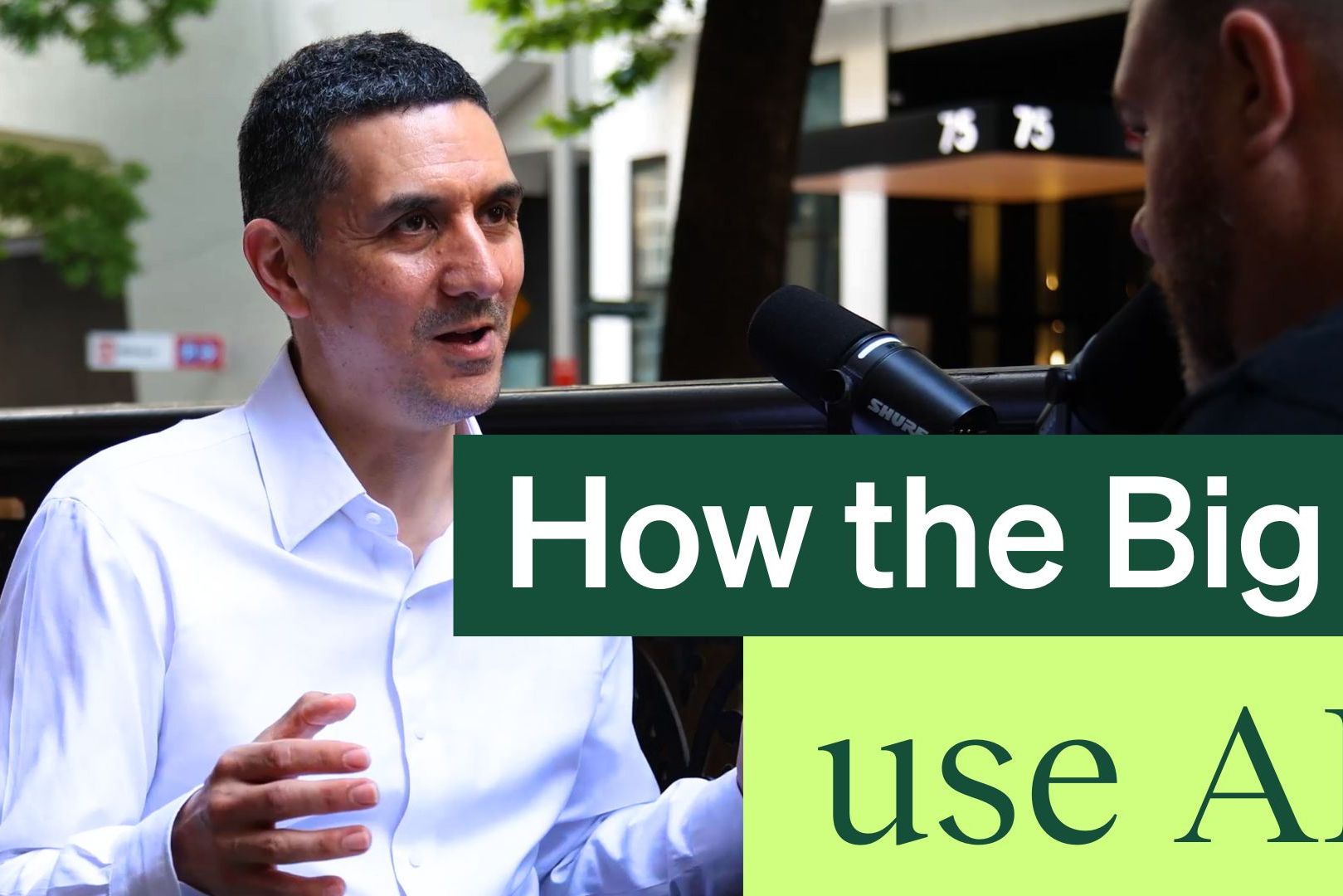 A man in a white shirt speaks during an outdoor interview, with text overlay: "How the Big 4 use AI."