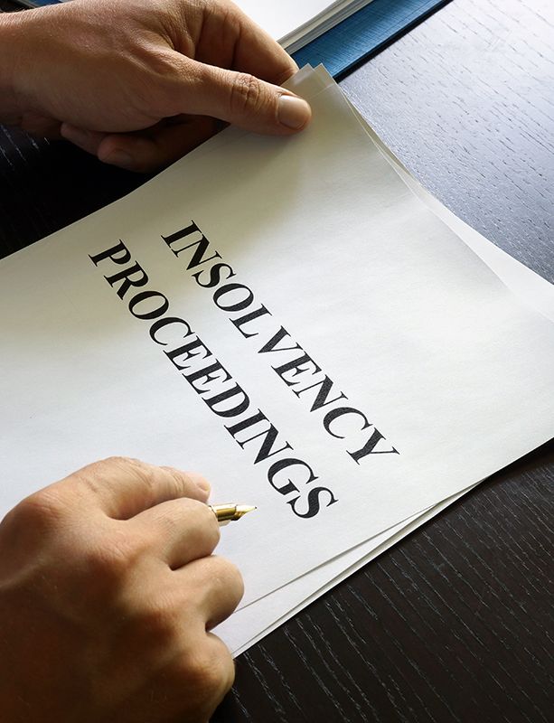 a person is writing on a piece of paper that says insolvency proceedings .