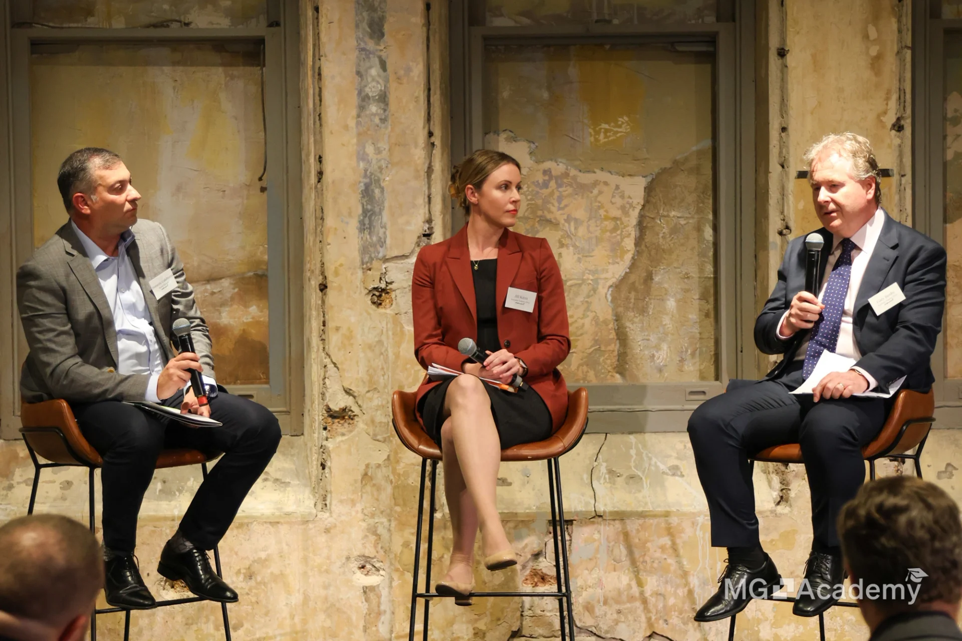 Three panelists, two men and one woman, seated with microphones.