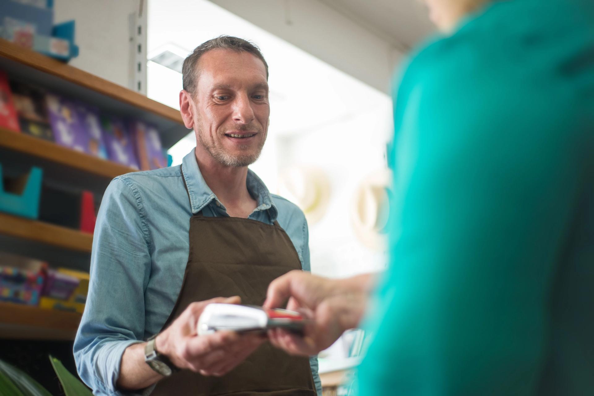 A retail store worker holding a card payment terminal for a customer