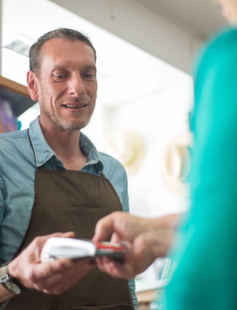 A retail store worker holding a card payment terminal for a customer