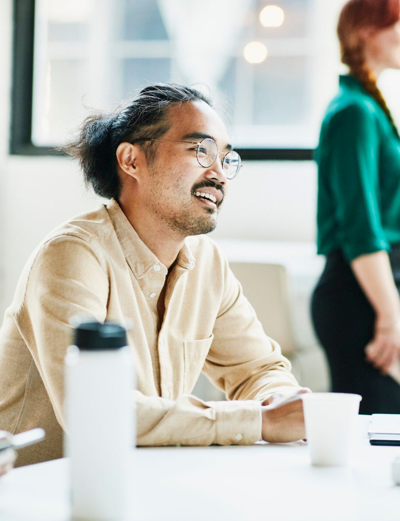 a man is sitting at a table with other people in an office .