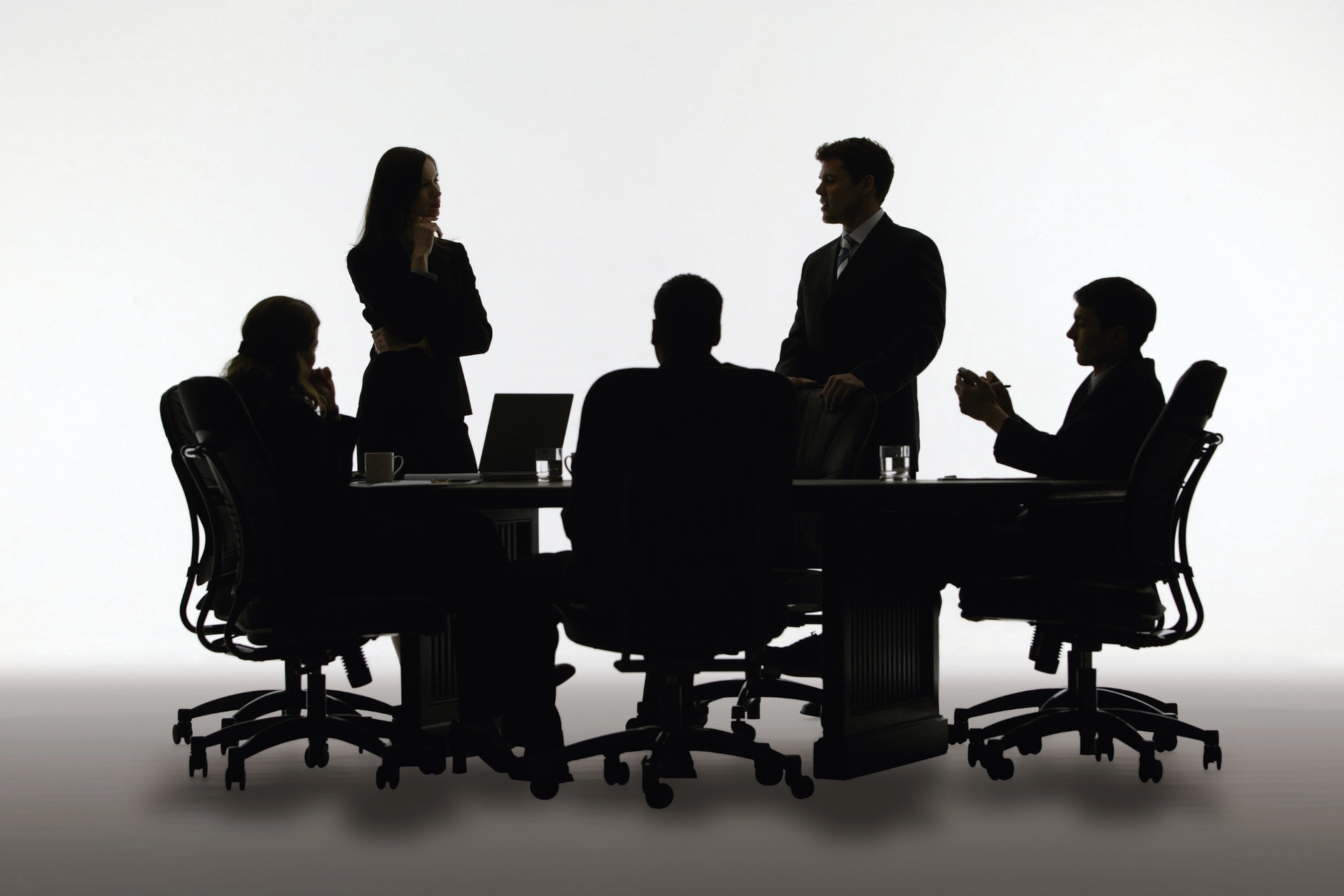 Five silhouetted business people at a meeting table.