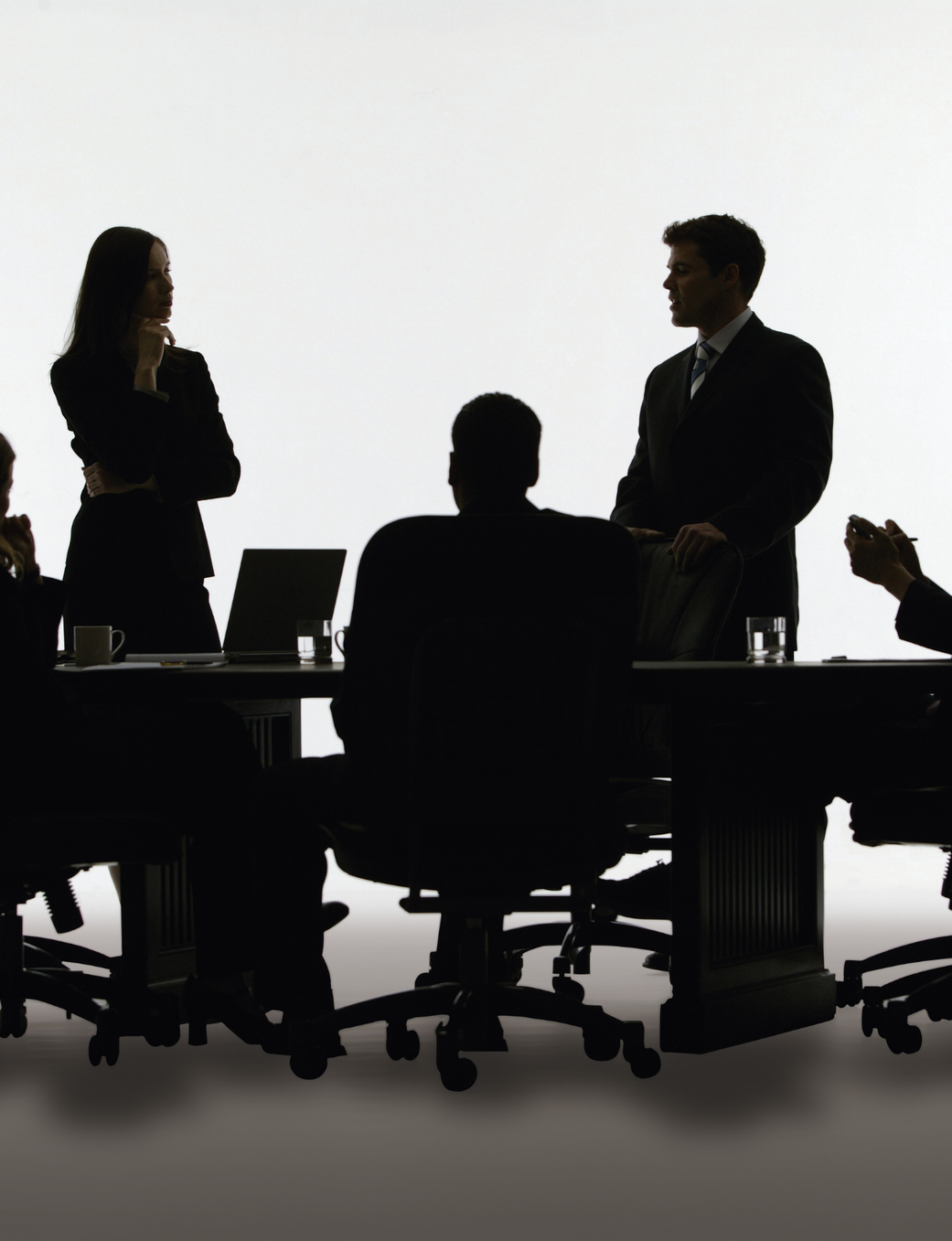 Five silhouetted business people at a meeting table.