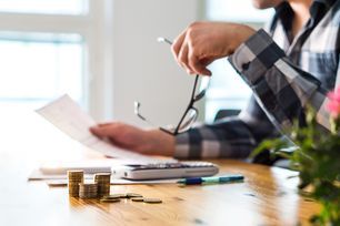 a man is sitting at a table with a calculator and stacks of coins .