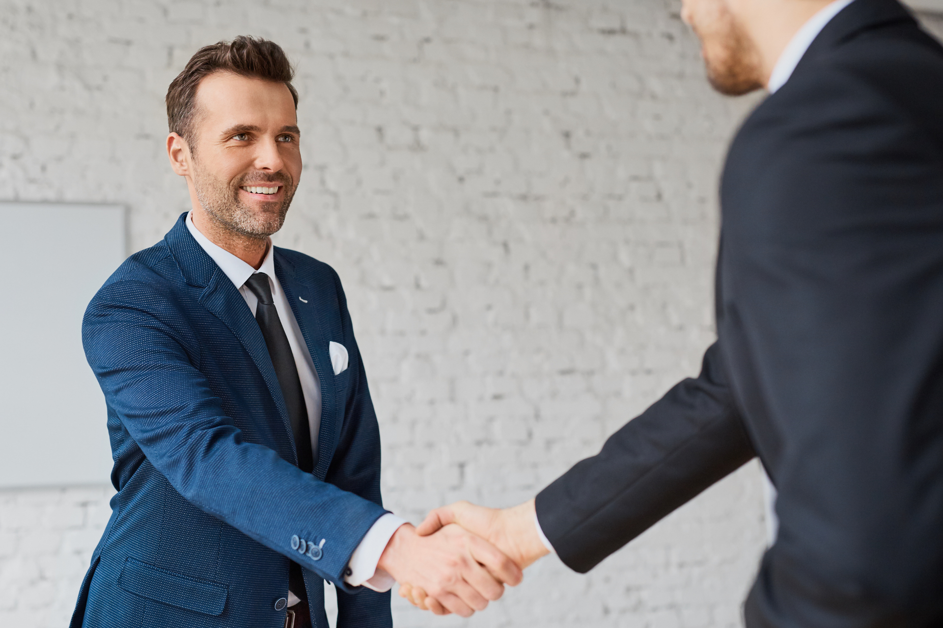 Two businessmen in suits shake hands.