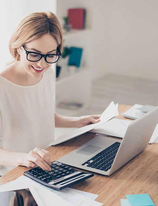 a woman is sitting at a desk with a laptop and a calculator .
