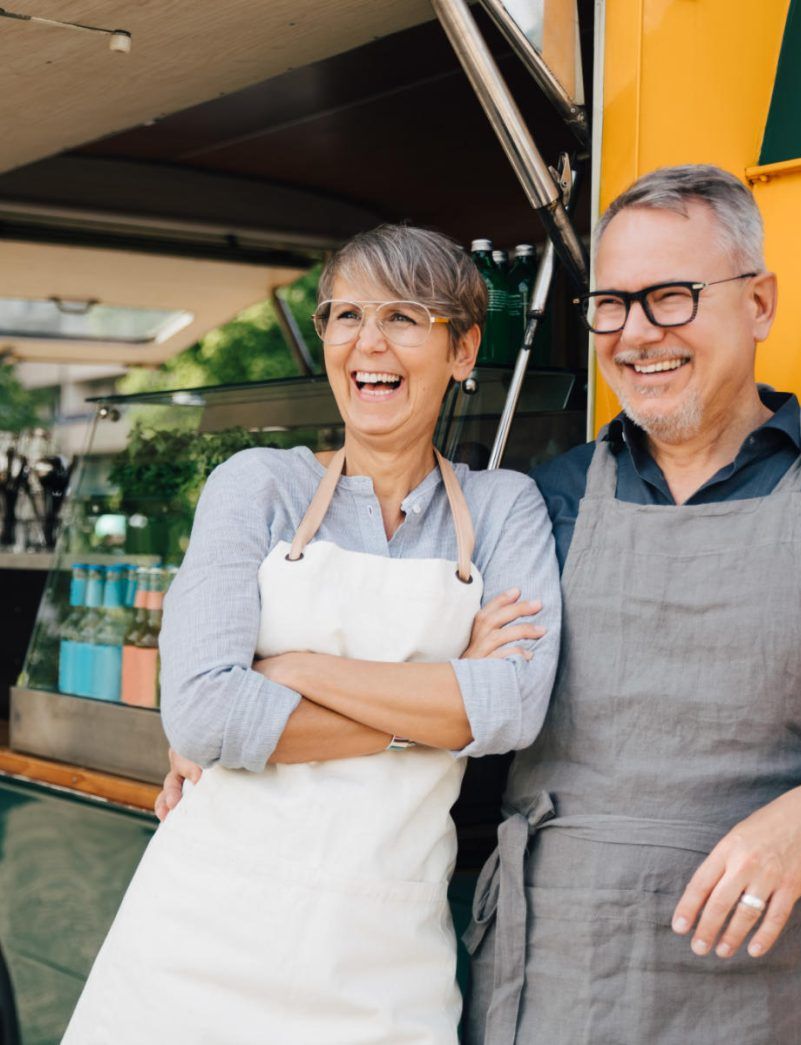 a man and a woman are standing next to a food truck .