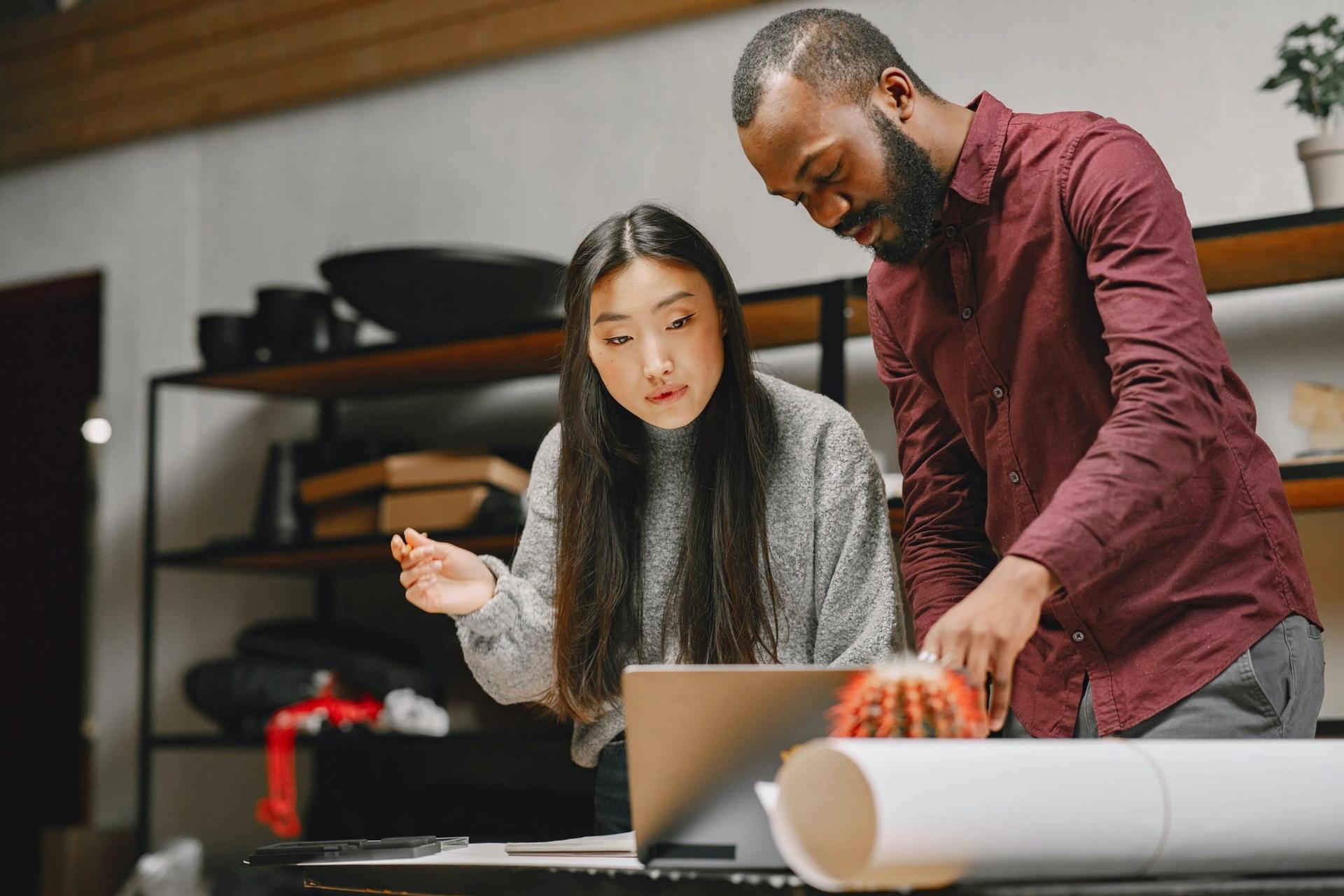 a man and a woman are looking at a laptop computer .