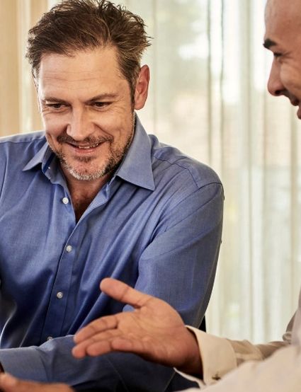 Two smiling men engaged in conversation, one gesturing.