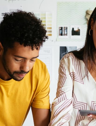 a man and a woman are looking at a tablet together .