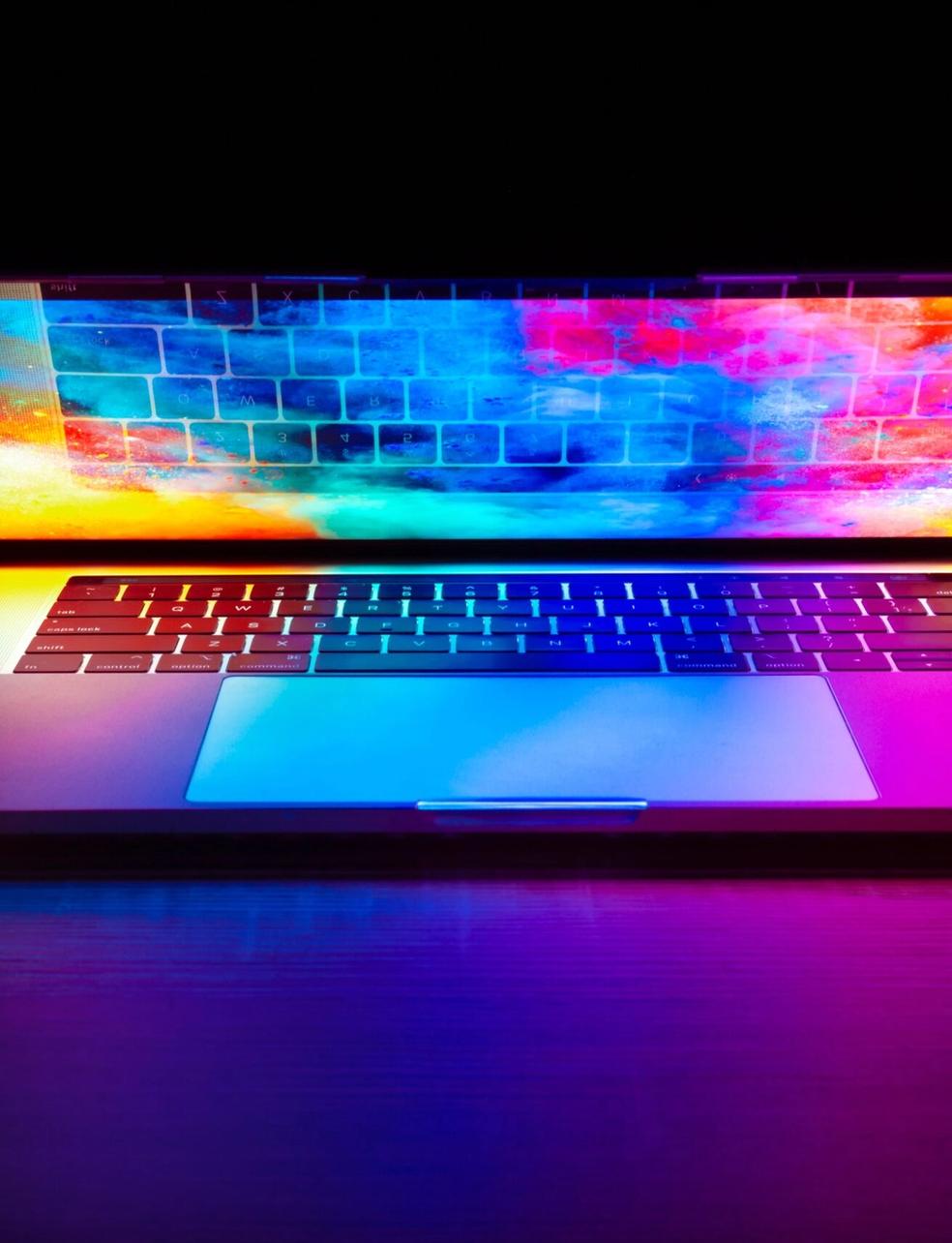 a laptop computer with a colorful screen is sitting on a wooden table .