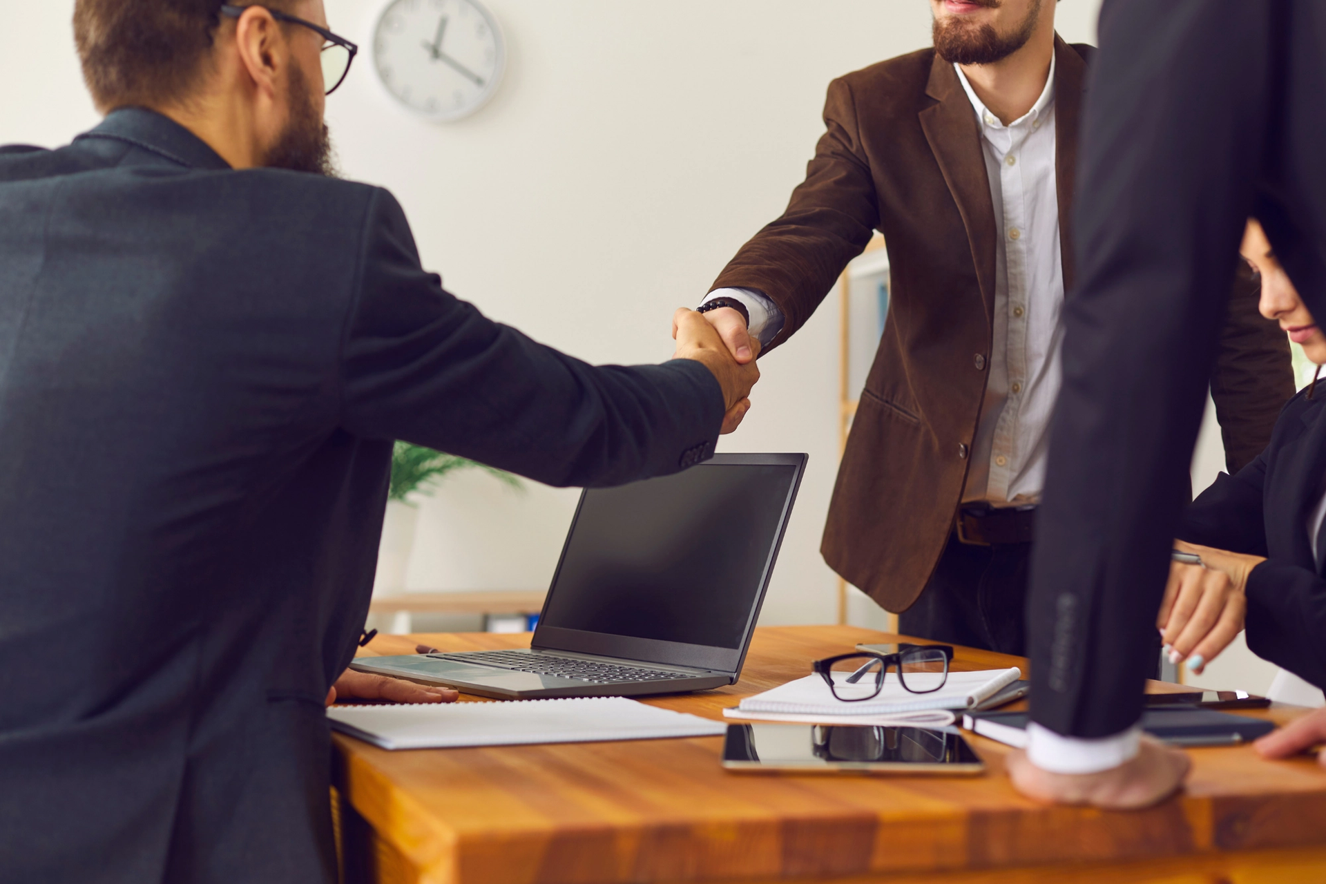 Two businessmen shaking hands across a meeting table.