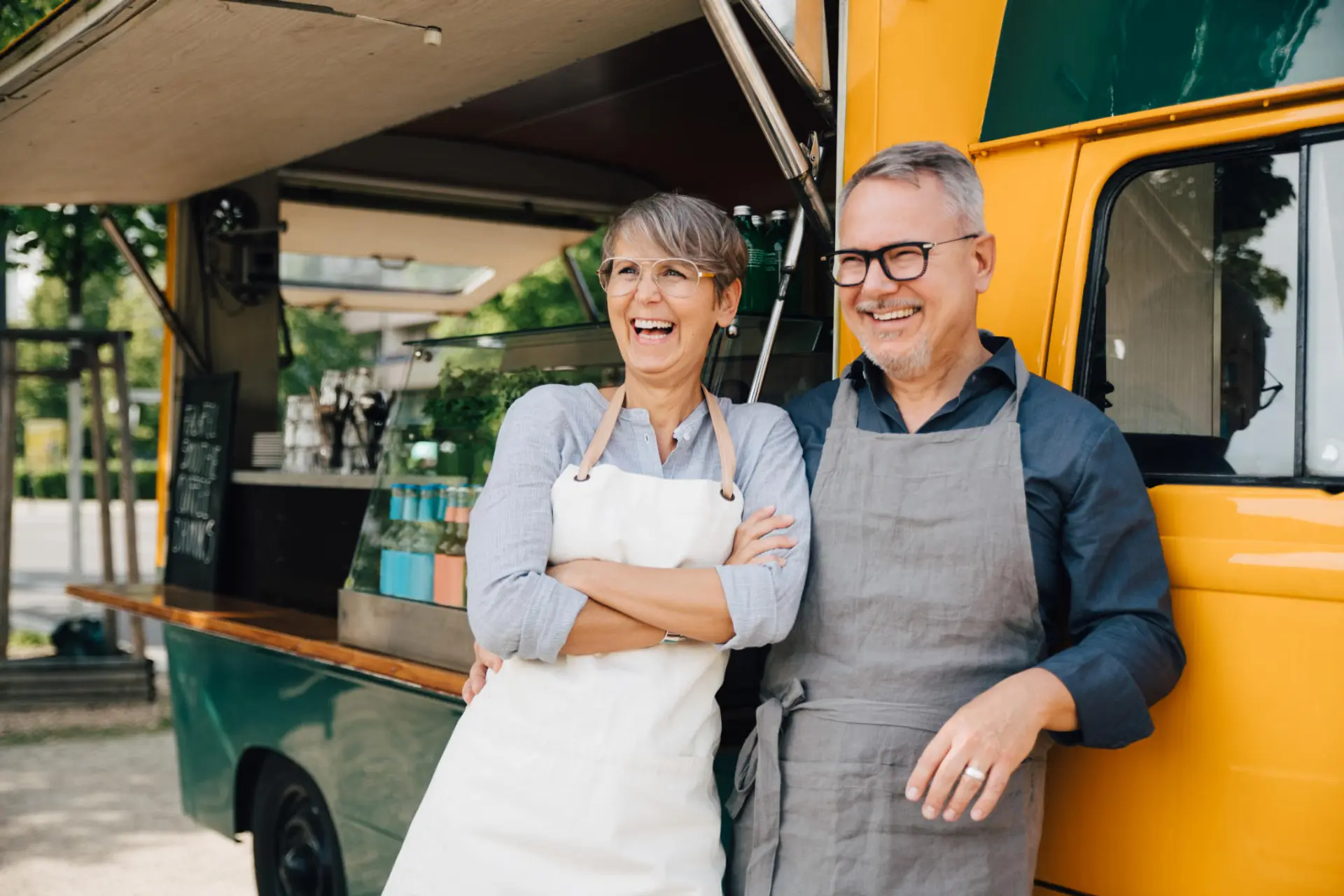 a man and a woman are standing in front of a food truck .
