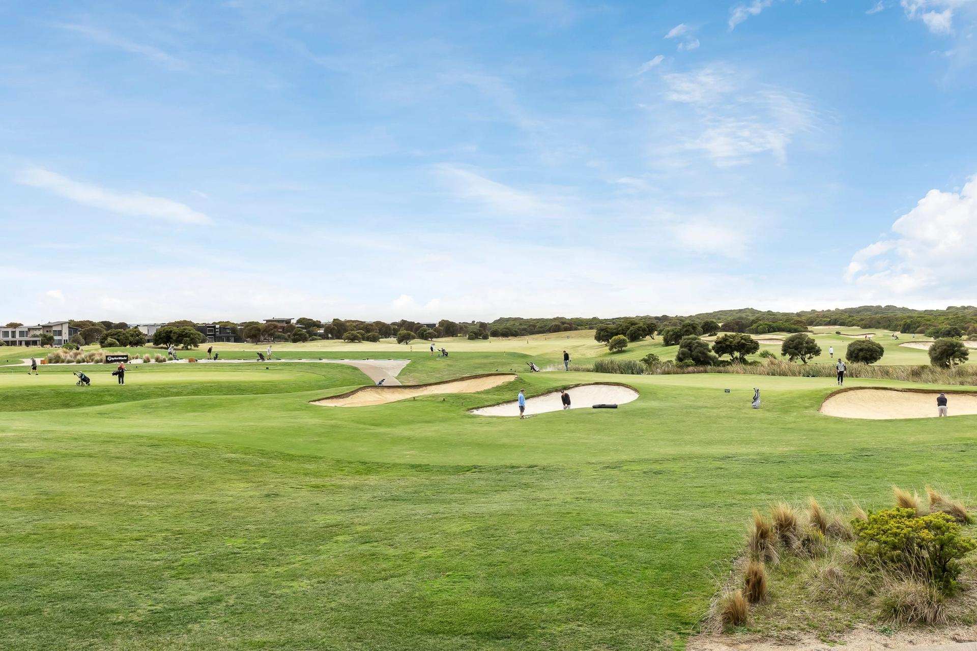 a group of people are playing golf on a golf course .