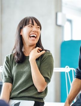 a man and a woman are laughing together in an office .