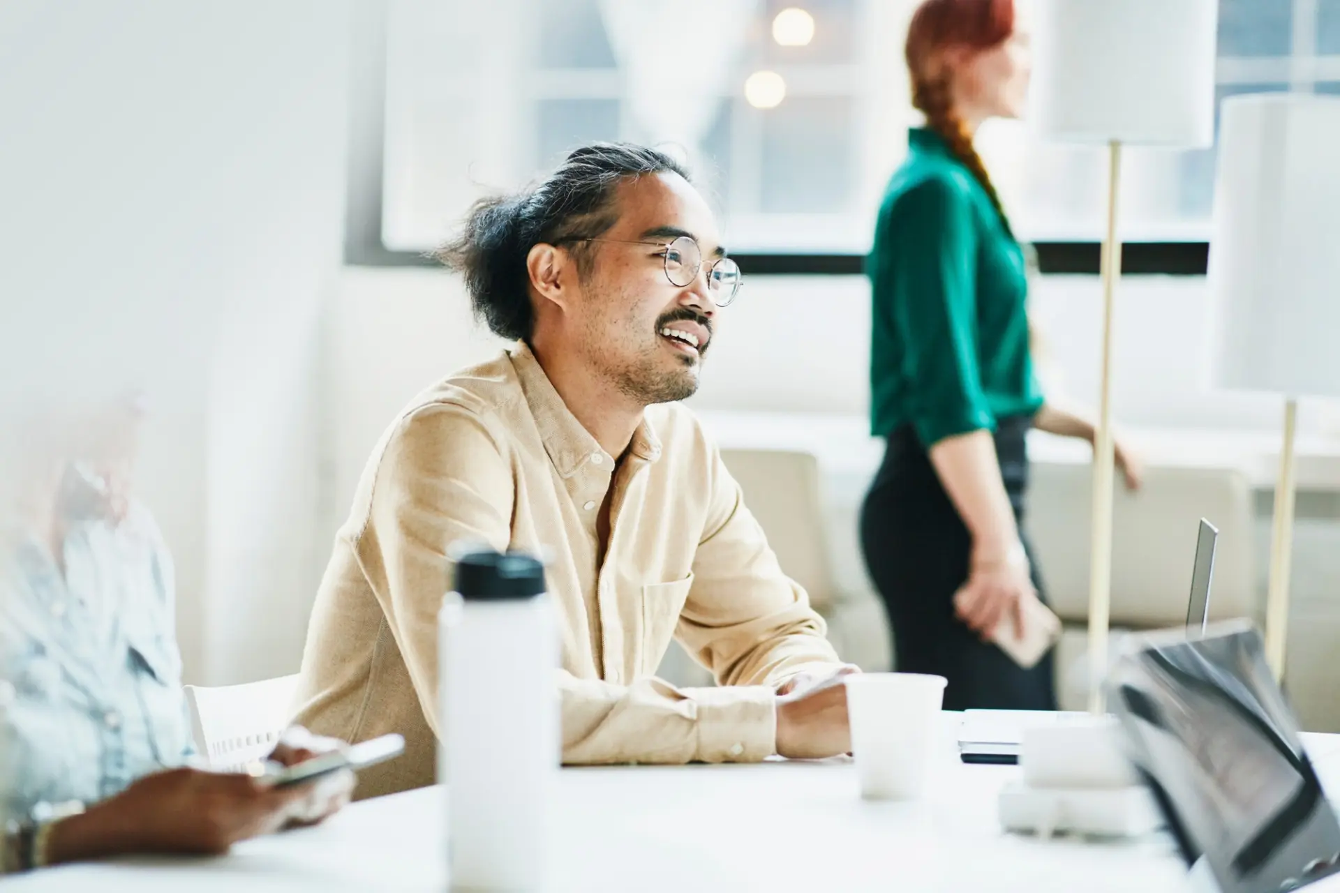a man is sitting at a table with other people in an office .